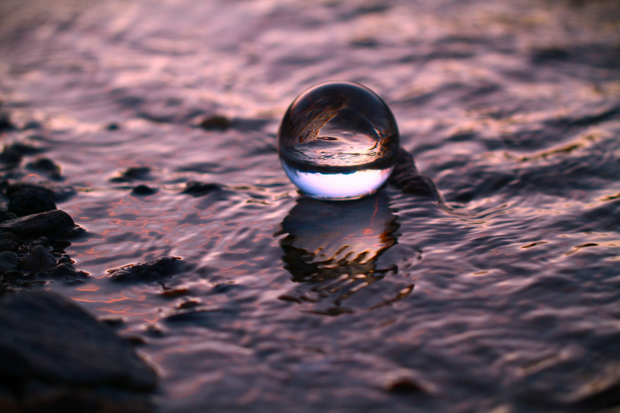 Sphère de verre posée sur un rivage rocheux
